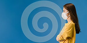 Young Asia girl wearing medical face mask with dressed in casual cloth and look at blank space isolated on blue background.