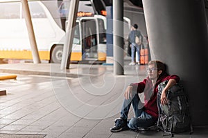 Young asia man with backpack sit and waiting bus in bus station, Selective focus, Travel concept