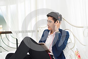 Young Asia man relaxing on the bed, listening to music with head