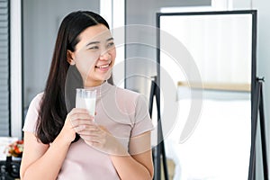 Young Asia woman drinking milk in the bedroom. Feeling happy smile and refreshment