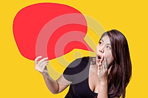 Young Asia woman holding red speech bubble on yellow background. Asian female show sign speech bubble banner, pretty girl look