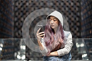 Young asia woman sending sms on cellphone in the mall
