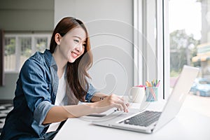 Young Asia woman smiling and looking at laptop screen