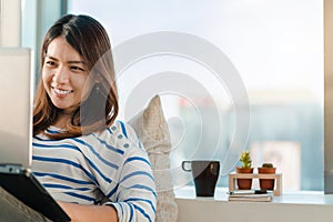 Young asia woman working on a laptop and sit on sofa at home office, Copy space, Selective focus