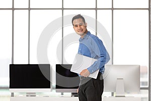 Young Asiabn businessman standing and holdin new laptop computer