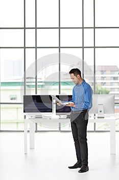 Young Asiabn businessman standing and holdin new laptop computer