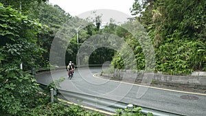 young asian adult cyclists riding bike on rural road