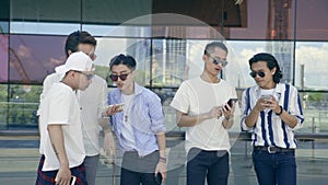 Young asian adult men hanging out on street looking at mobile phone