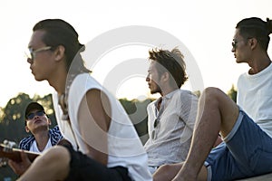 Young asian adult men sitting on beach