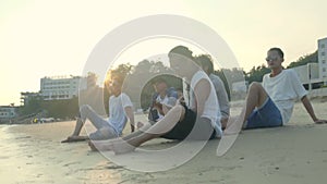 Young asian adult men sitting on beach relaxing singing playing guitar