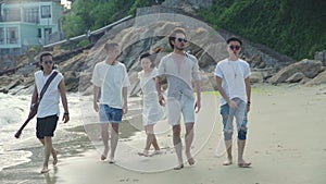 Young asian adults men and women having fun walking on beach