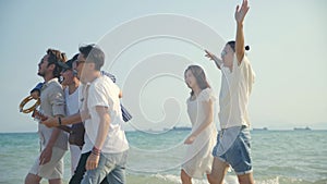 Young asian adults men and women having fun walking singing on beach