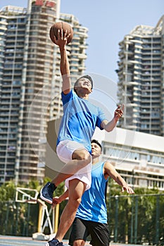 Young asian adults playing basketball