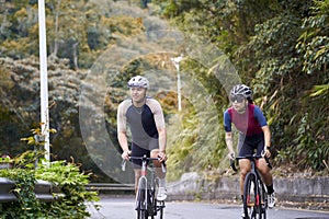 young asian adults riding bike on rural road