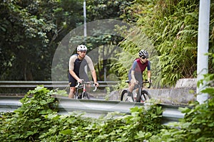 young asian adults riding bike on rural road