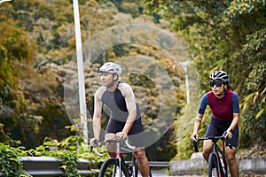 young asian adults riding bike on rural road