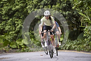 young asian adults riding bike on rural road