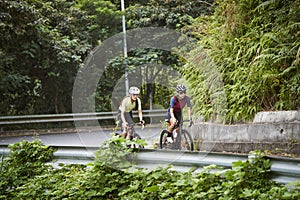 young asian adults riding bike on rural road