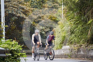 young asian adults riding bike on rural road