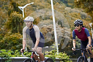 young asian adults riding bike on rural road