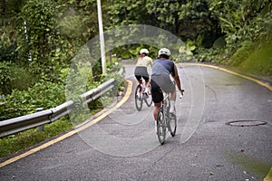 young asian adults riding bike on rural road