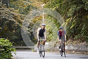 young asian adults riding bike on rural road photo