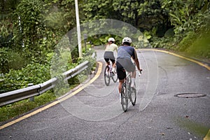young asian adults riding bike on rural road photo