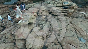 Young asian adults walking on rocks by the sea