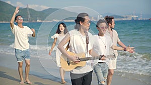 Young asian adults walking singing on beach