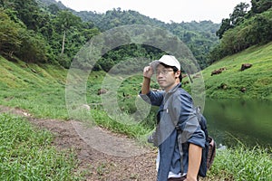 Young Asian adventure man looking at camera with nature green mountain background. Travel lifestyle and relaxation concept