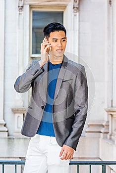 Young Asian American Male College Student talking on cell phone inside old style office building in New York City