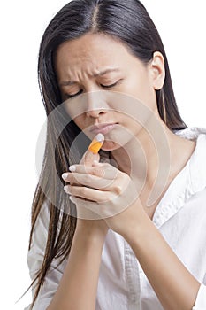 Young Asian American woman with injjured finger on white background