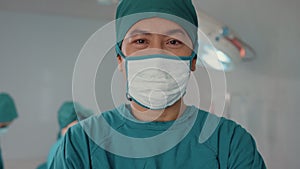 Young Asian assistants man looking at camera and smiling after performing invasive surgery on patient in hospital operating room.