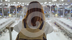 Young Asian backpacker woman looking around in terminal hall while waiting her flight at the departure gate in international