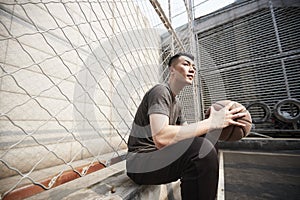 Young asian basketball player resting at courtside