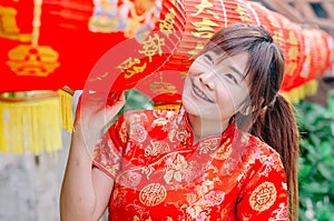 Young asian beautiful girl in chinese traditional red dress smile stand near china lamp, in the Chinese New Year. Festivities.