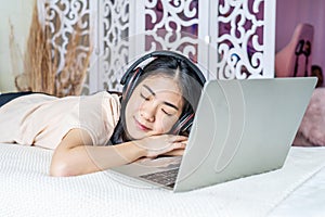 Young asian beautiful internet addict woman in pajamas on bed at home bedroom asleep while working with laptop computer, Resting