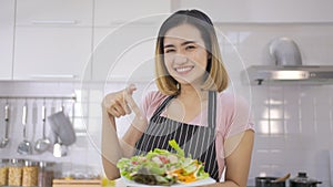 Young asian beautiful smiling woman making vegetable salad in the kitchen