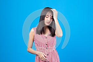 Young Asian beautiful woman wearing red dress on blue background suffering from headache desperate and stressed because pain and