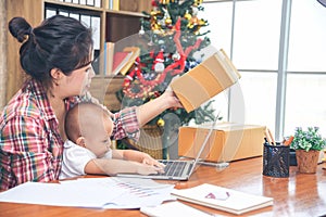 Young Asian beautiful women working at home, and take care of daughter. Baby girl sitting with mother and playing mother laptop.