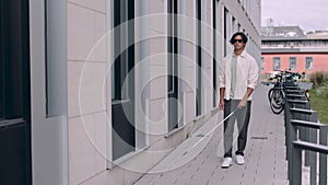 Young asian blind man with using safety stick for walking alone outdoors. Male person wearing glasses and casual clothes