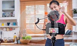 Young Asian blogger holding dumbbell while recording video on camera at home.media influencer reviewing and marketing concept