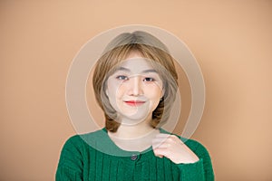 Young asian blonde woman wearing casual green winter sweater smiling looking confident at the camera