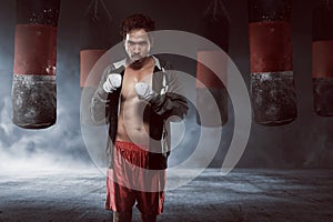 Young asian boxer man in a black robe with punching bag