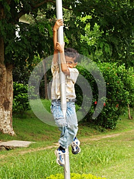 Young Asian boy climbing pole