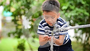 Young Asian boy drink a water from faucet on green background