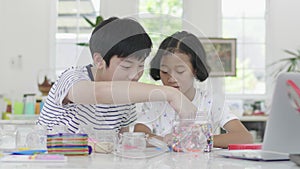 The young asian boy and girl are playing with the jigsaw puzzle with smile face.