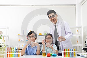 Young Asian boy and girl smile and having fun while doing science experiment in laboratory classroom with Teacher. Study with