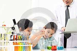 Young Asian boy and girl smile and having fun while doing science experiment in laboratory classroom with Teacher. Study with