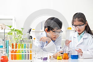 Young Asian boy and girl smile and having fun while learning science experiment in laboratory with teacher in classroom. Study
